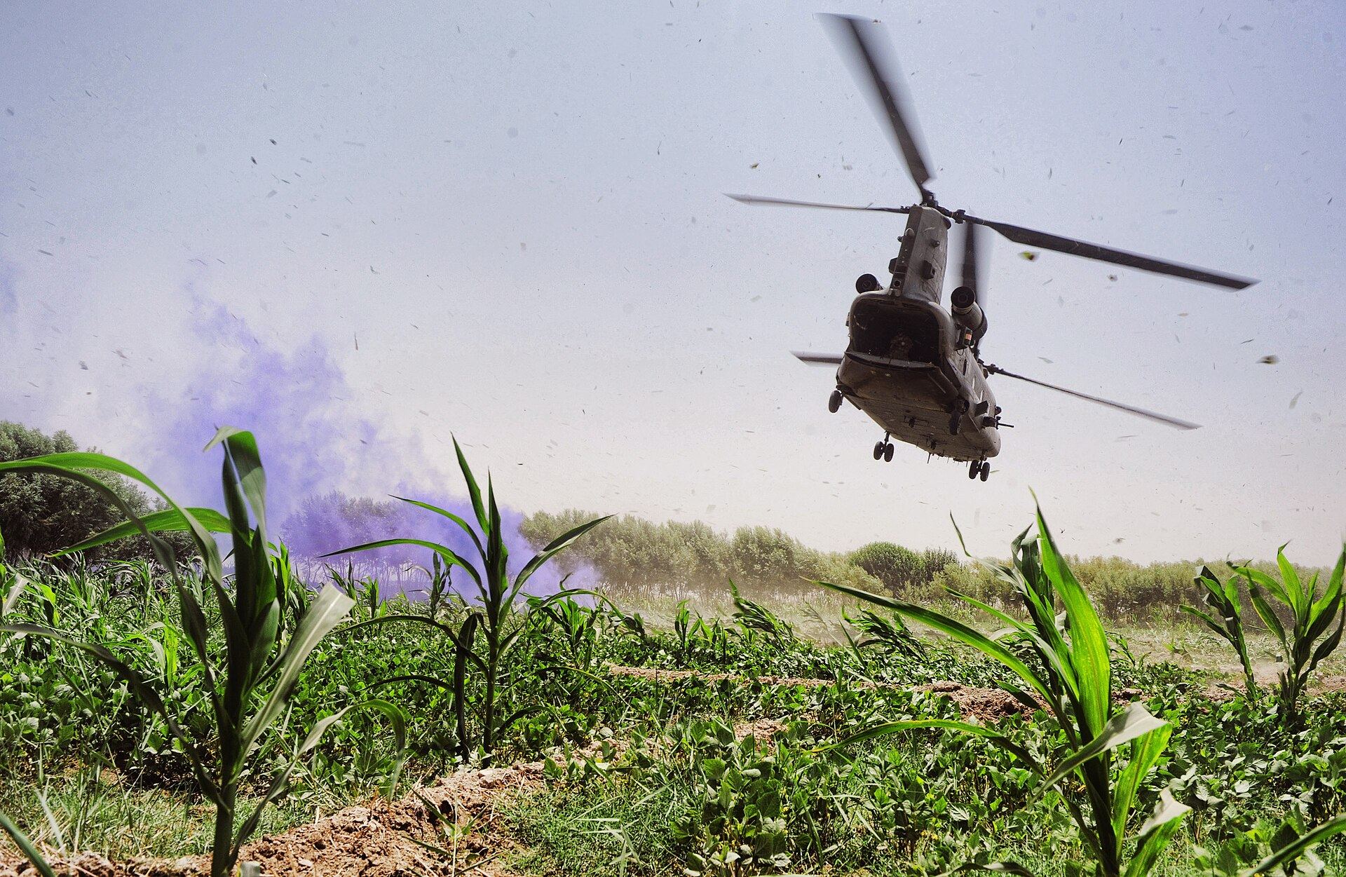 An RAF Chinook lifts off with a casualty in Afghanistan, coloured smoke marking the landing site